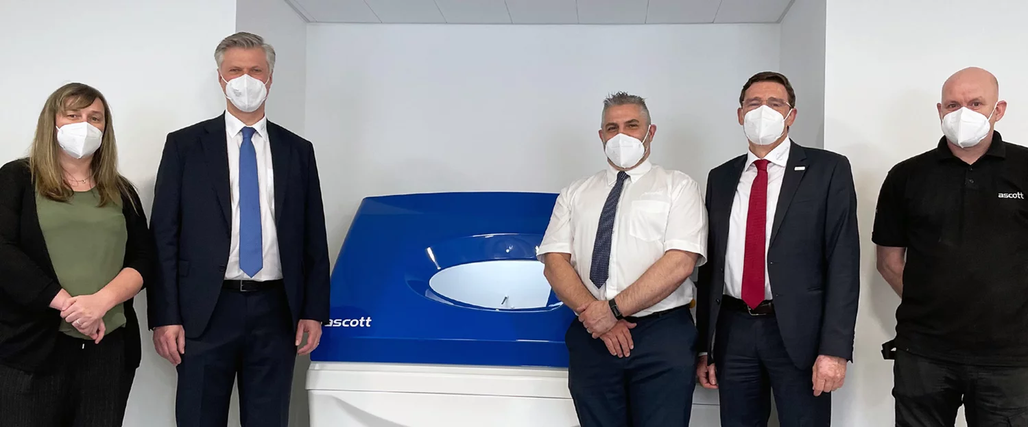 5 people stand around the corrosion testing system and look into the camera