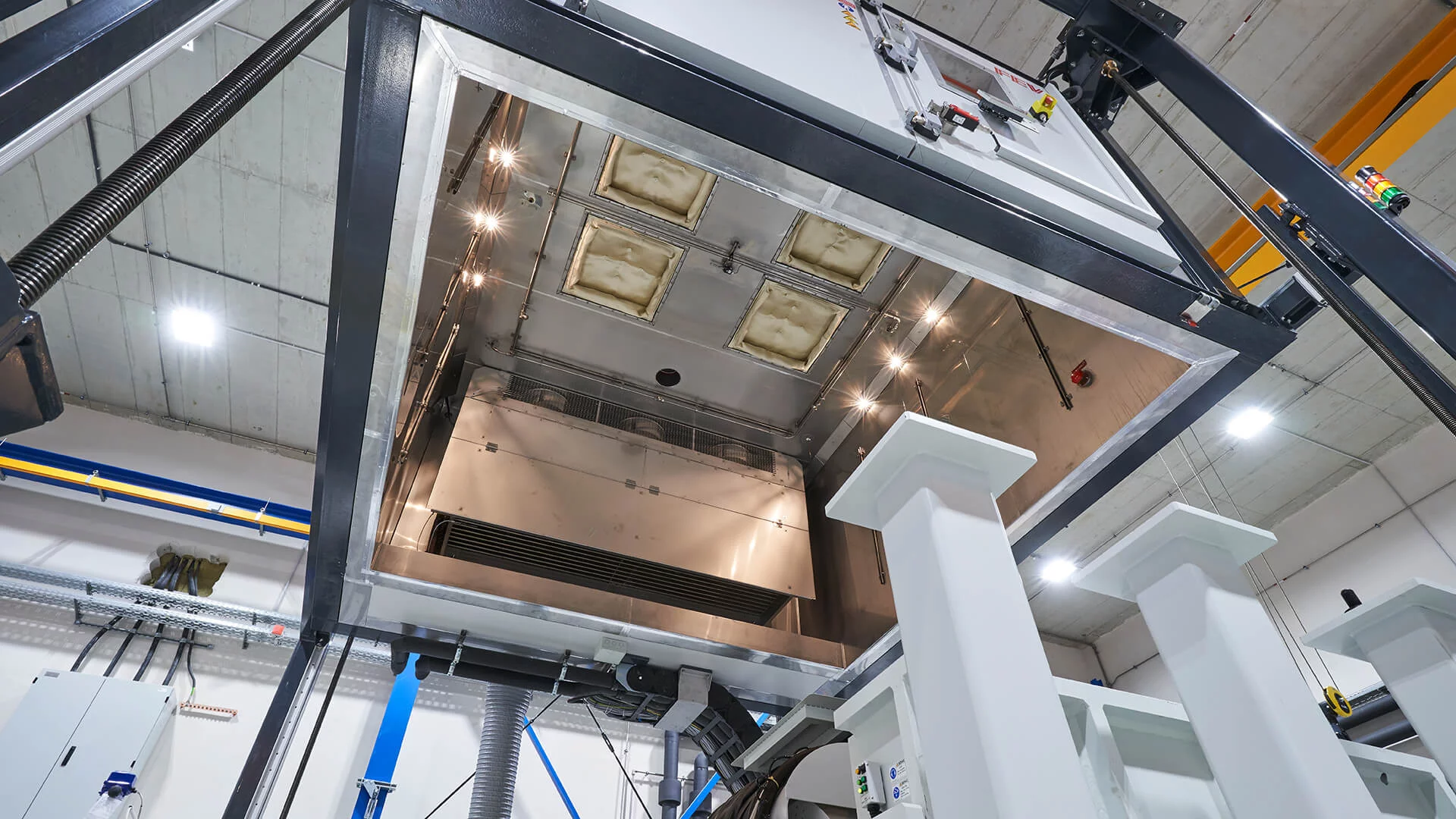  Innenansicht einer industriellen Vibrationstest-Prüfkammer mit Edelstahlverkleidung, Beleuchtung und isolierter Decke