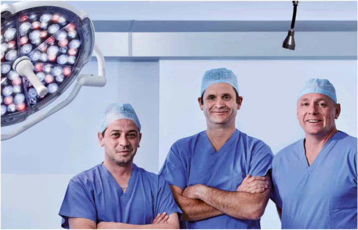Medical surgical team under operating light in a hygienically climate‑controlled hospital operating room by Weiss Technik