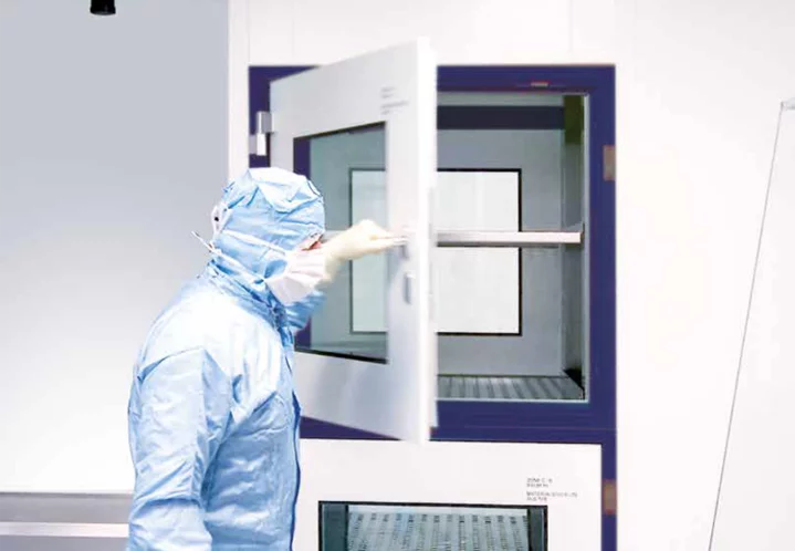 Operator in cleanroom garments using a material airlock in cleanroom technology for pharmacy compounding.